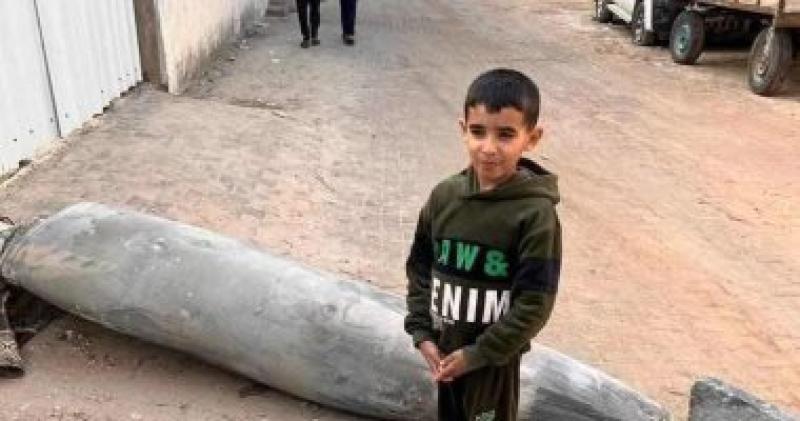 أطفال رمز الشجاعة.. طفل فلسطينى يلقط صورة بجوار صاروخ إسرائيلي